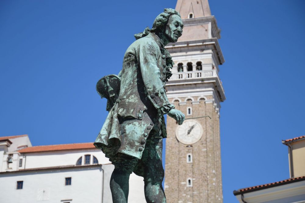 Piran a socha rodáka Giuseppe Tartiniho, vzadu kostel se zvonicí
