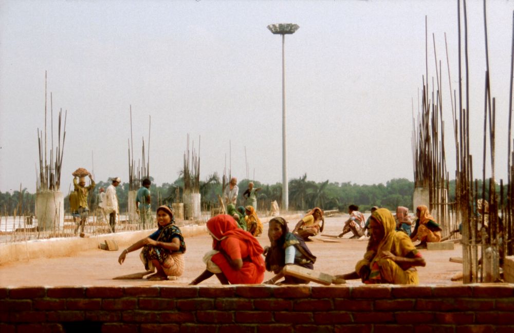 Ruční stavba letištní budovy: ženy ručně uplácavájí beton.
